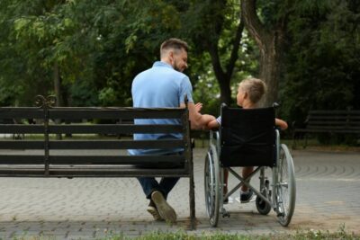 criança sentada com pai em banco de praça
